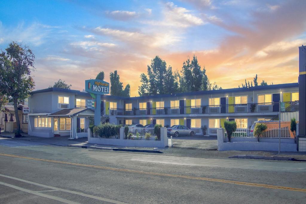 um edifício de hotel com uma placa de motel em frente em Highlander Motel em Oakland