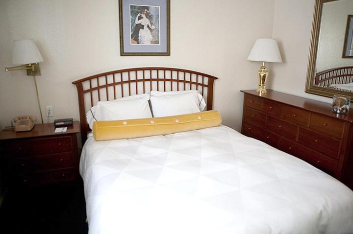 a bedroom with a large white bed and two dressers at Coral Reef Inn & Condo Suites in Alameda