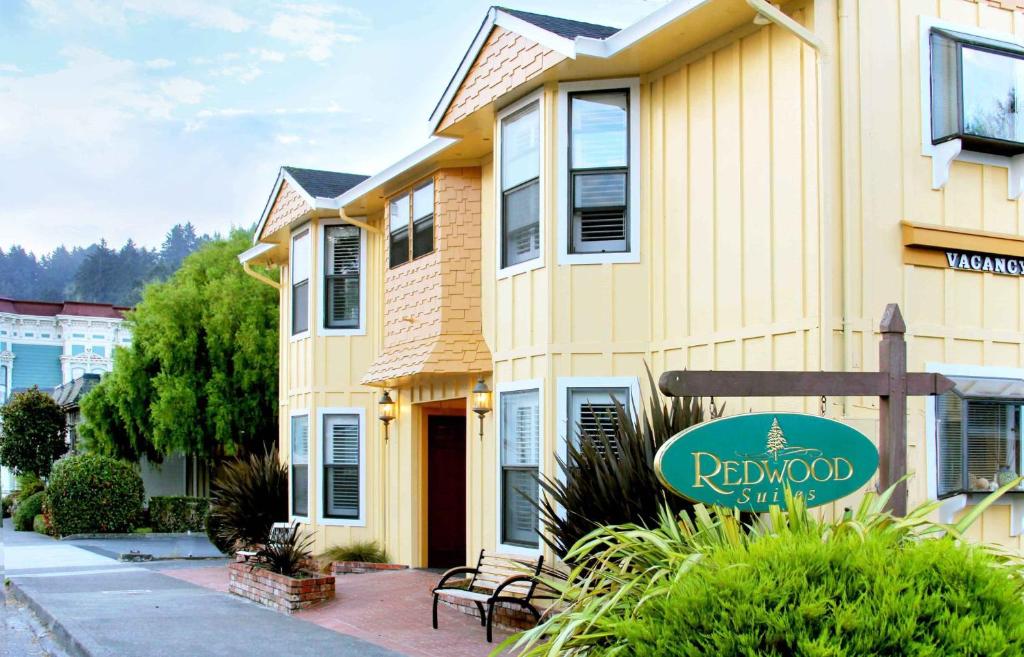 una casa amarilla con un letrero de madera roja delante de ella en Redwood Suites, en Ferndale