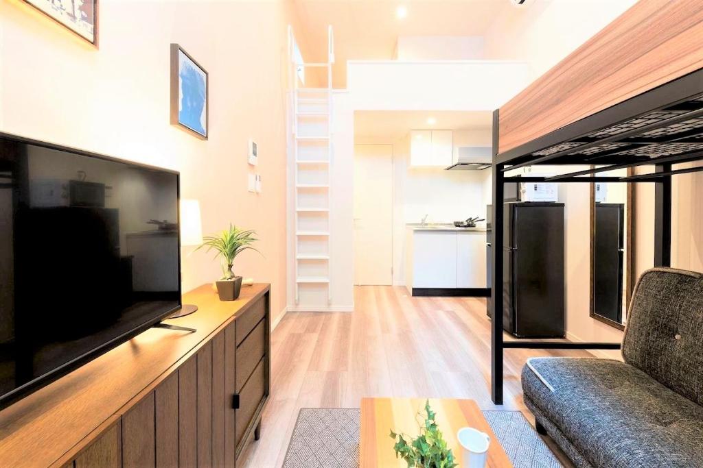 ein Wohnzimmer mit einem großen TV und einem Sofa in der Unterkunft TRIP POD TOJIN-MACHI A in Fukuoka