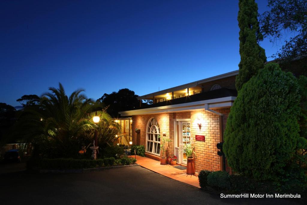 a brick house with lights on it at night at Summerhill Motor Inn in Merimbula