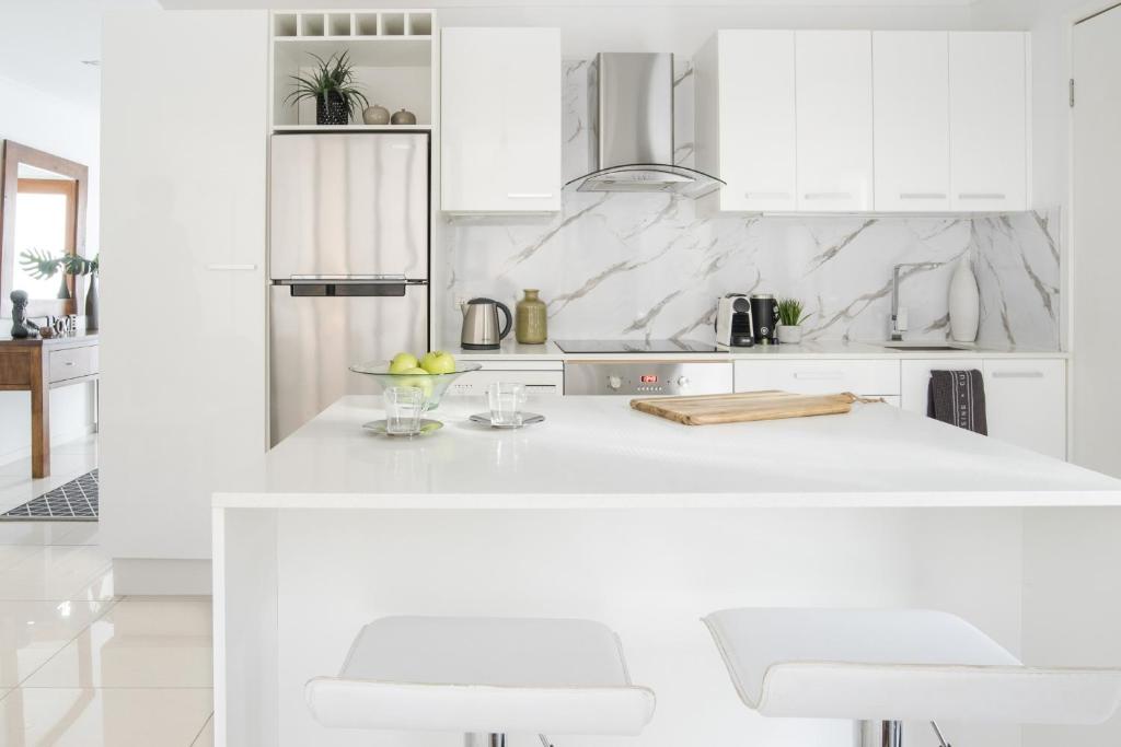 una cocina blanca con armarios blancos y encimeras blancas en Immaculate Apartment close to Brisbane City and Airport en Brisbane