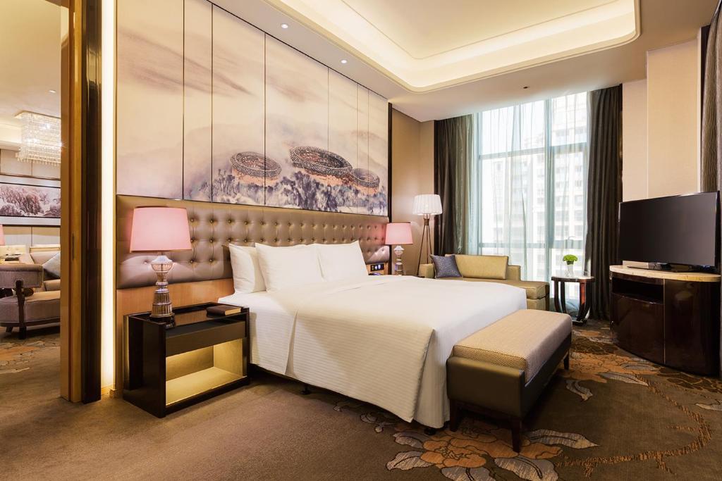 a hotel room with a large bed and a television at Wanda Realm Longyan in Longyan