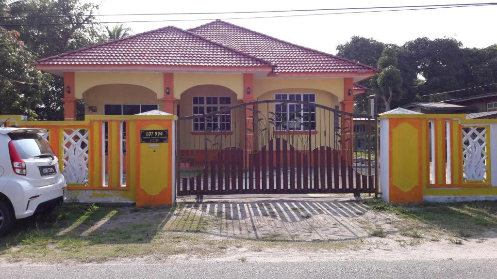 uma casa com um portão em frente em Farah Banglo Homestay Kemasik em Kemasik