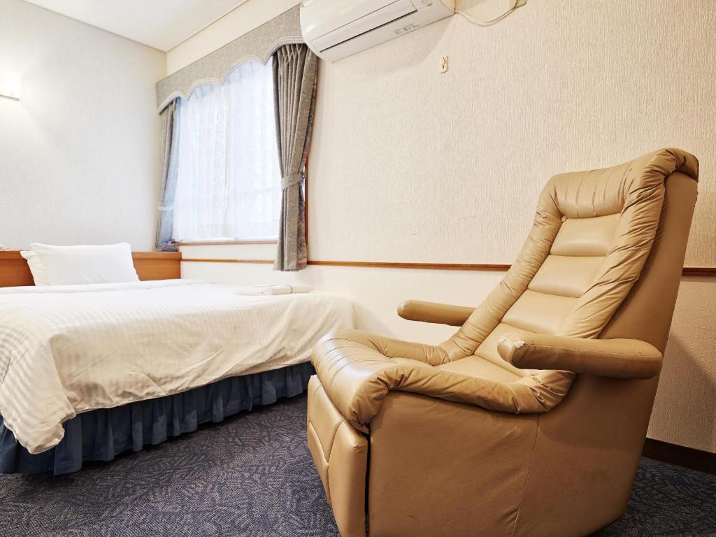a hotel room with a bed and a chair at Crown Hotel Okinawa in Okinawa City
