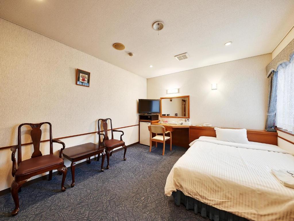 a hotel room with a bed and chairs and a desk at Crown Hotel Okinawa in Okinawa City