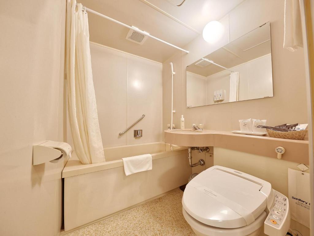 a white bathroom with a toilet and a sink at Crown Hotel Okinawa in Okinawa City