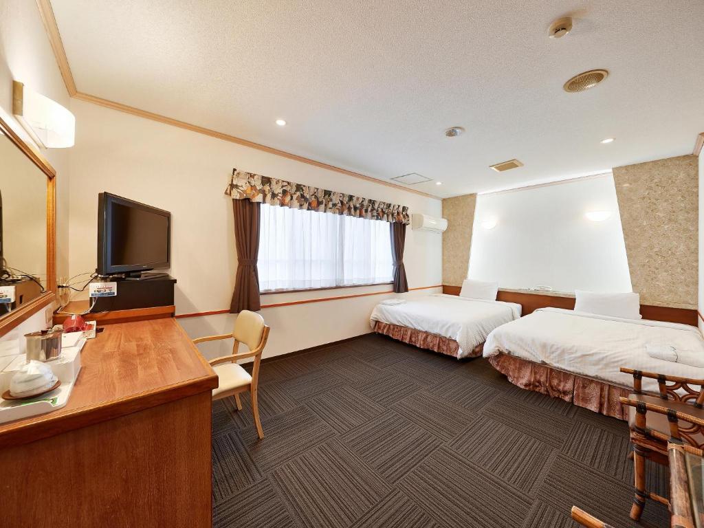 a hotel room with two beds and a flat screen tv at Crown Hotel Okinawa in Okinawa City