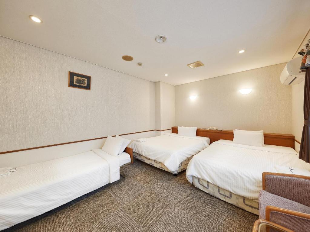 two beds in a room with white sheets at Crown Hotel Okinawa in Okinawa City