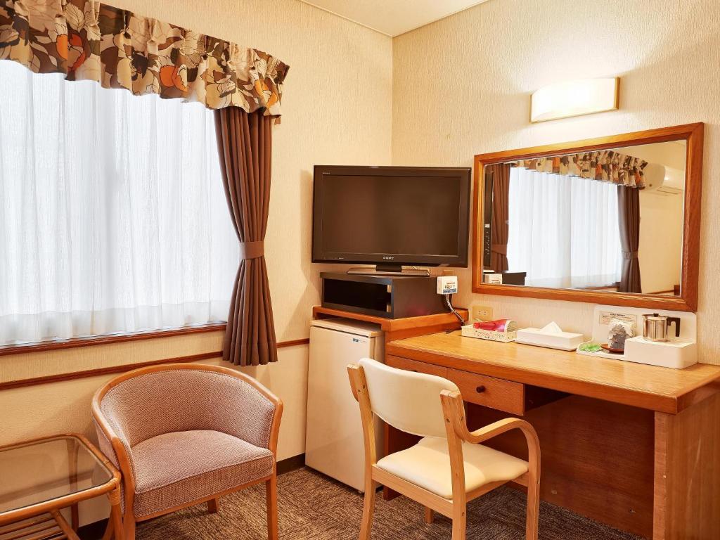 a hotel room with a desk and a television at Crown Hotel Okinawa in Okinawa City