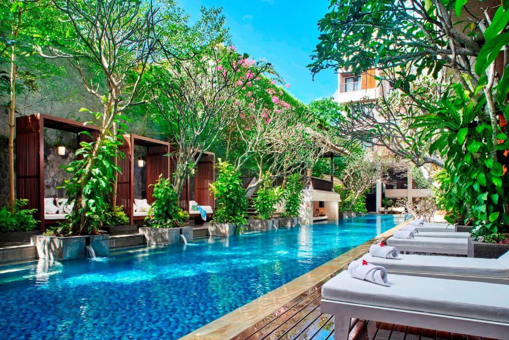 una piscina in un resort con sedie a sdraio di Jambuluwuk Oceano Seminyak Hotel a Seminyak