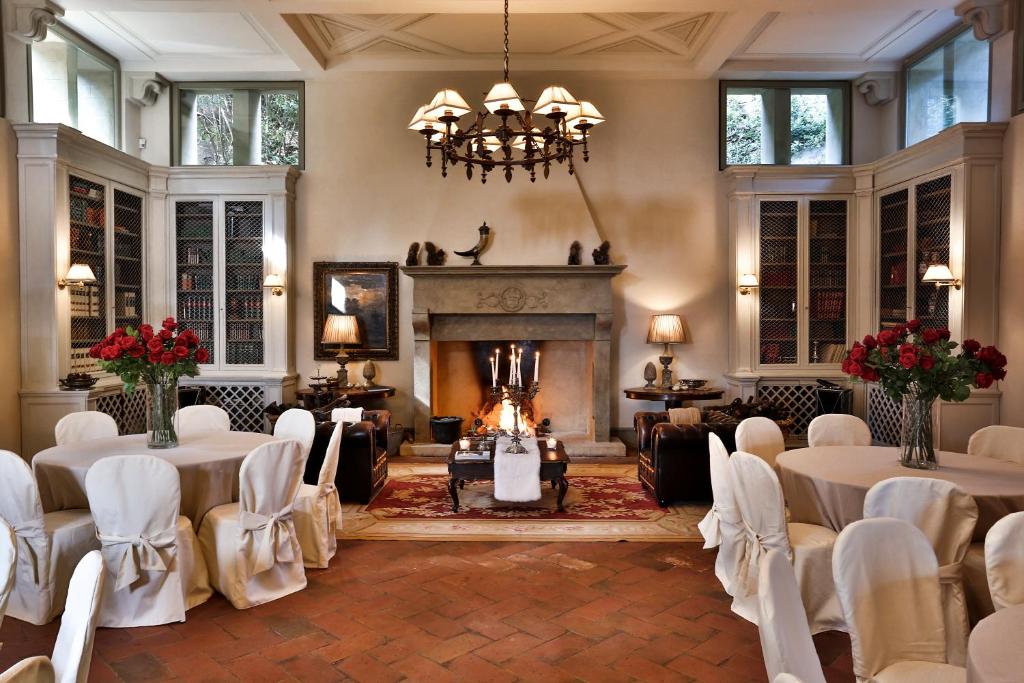 een kamer met tafels en stoelen en een open haard bij Villa Le Fontanelle in Florence