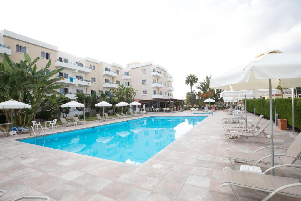 a swimming pool with chairs and umbrellas next to a building at DebbieXenia Hotel Apartments in Protaras