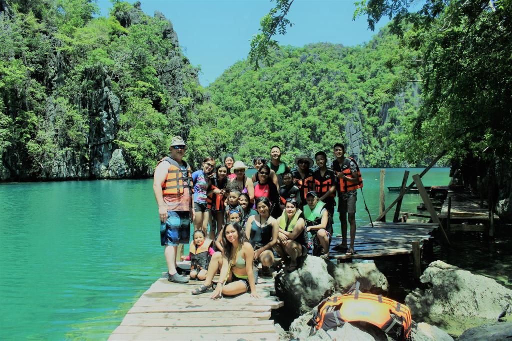 a group of people standing on a dock in the water at FilCan Hostel/Backpackers in Coron