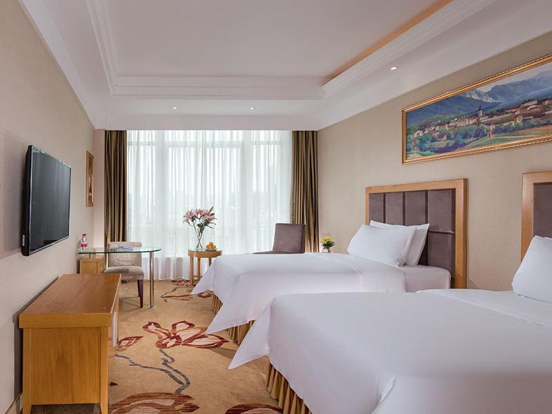 a hotel room with two beds and a television at Vienna Hotel (Shajinbei Road Fuquan Guizhou) in Fuquan