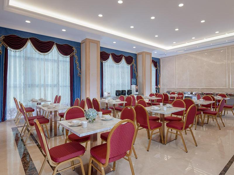 a dining room with tables and red chairs at Vienna Hotel (Qingyuan Century Bar Shop in Guangdong Province) in Qingyuan