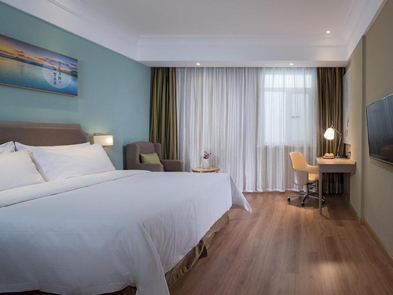 Chengmai的住宿－维也纳3好酒店 (海口澄迈老城店)，酒店客房设有一张大床和一张书桌。