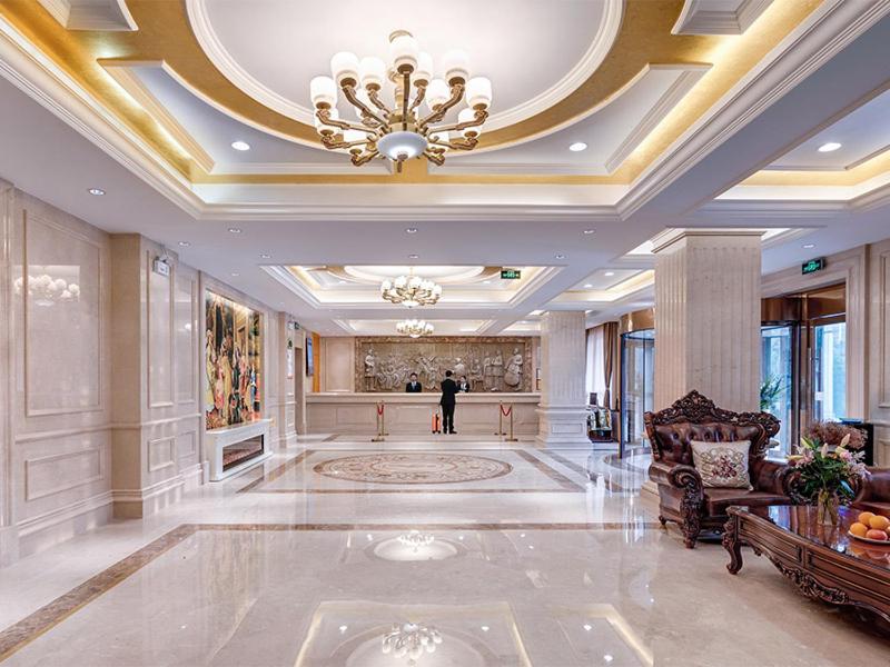 a large lobby with a chandelier and a person standing in it at Vienna Hotel(Shanghai Chongming Lvhai Road.) in Shanghai