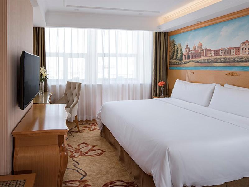 una camera d'albergo con un grande letto e una TV di Vienna Hotel(Shenzhen Shajing Jingjinbaina Branch) a Shenzhen