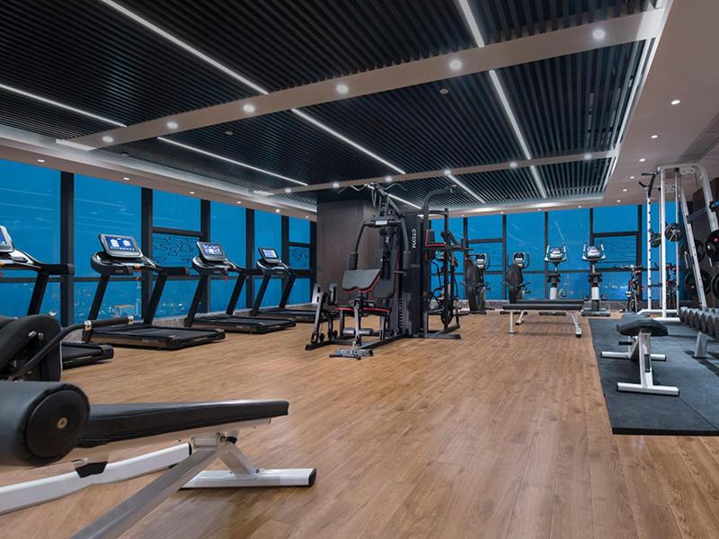 a gym with several treadmills and machines in a room at Venus Royal Hotel(Foshan Kuiqi Road Metro Station) in Foshan
