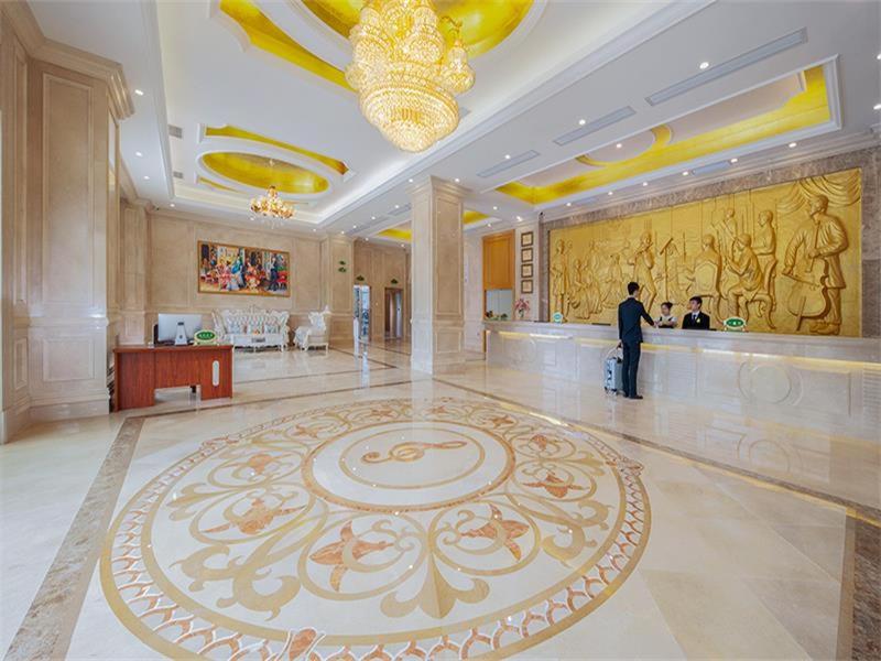 a man standing in a large lobby with a large rug at Vienna Hotel Huiyang Sanhe Square in Huizhou