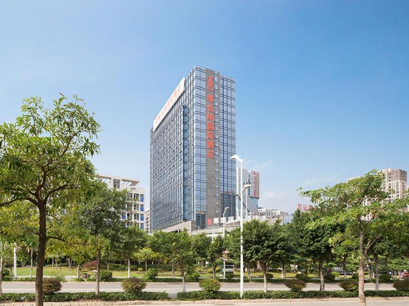 a tall building in a city with trees in front at Vienna International Hotel(Jinjiang Jordan Center) in Jinjiang