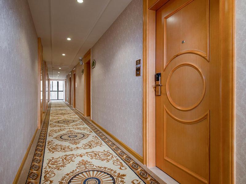 a hallway with a large wooden door and a tile floor at Vienna Hotel(Fuzhou Changle International Airport) in Fuzhou