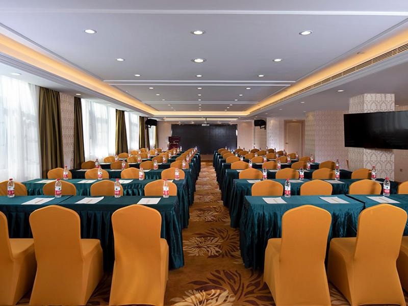 a conference room with tables and chairs and a screen at Vienna International Hotel (Hunan Changde Taoyuan Longba) in Taoyuan
