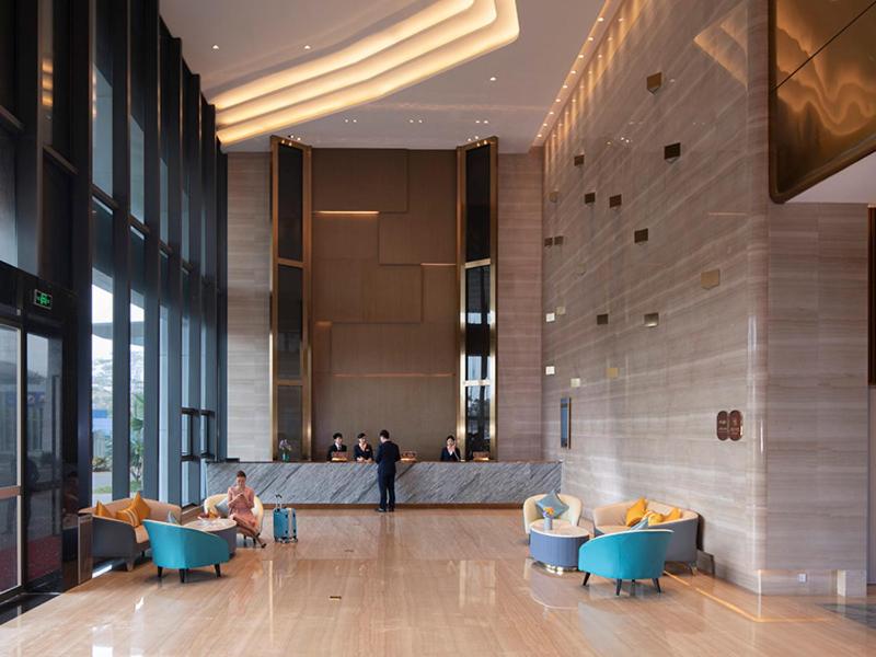 a lobby with people sitting in chairs in a building at Vienna Hotel(Haikou International Convention and Exhibition Center) in Haikou