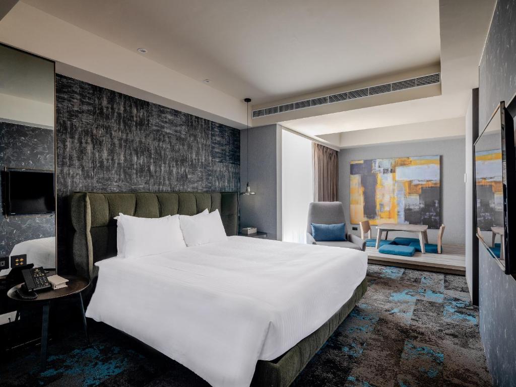 a bedroom with a large white bed and a chair at Kung Shang Design Hotel in Kaohsiung