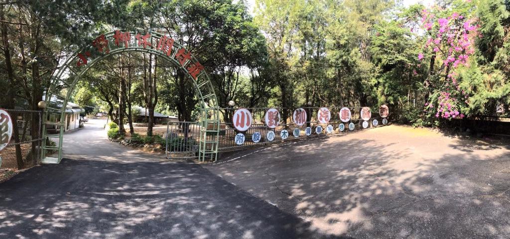 un parc avec une arche et un chemin arboré dans l'établissement Xiaoye Liu Homestay, à Guoxing