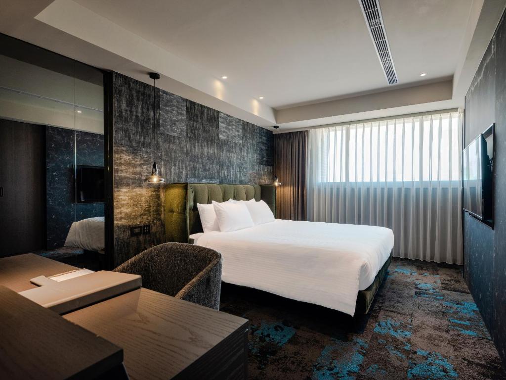 a hotel room with a large bed and a table at Kung Shang Design Hotel in Kaohsiung