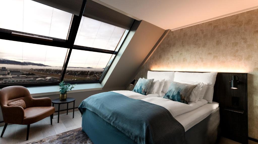 um quarto com uma cama grande, uma cadeira e janelas em Quality Hotel Panorama em Trondheim