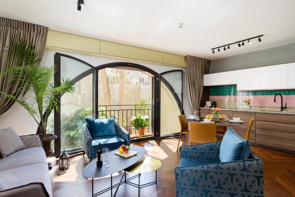 a living room with blue chairs and a table at Boutique & Comfort in David's Village by FeelHome in Jerusalem