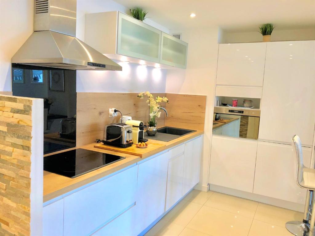 a kitchen with white cabinets and a sink at Appartement Cosy Calme Central-Terrasse Proche Palais in Cannes