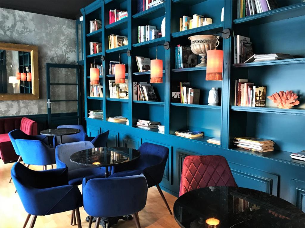 een kamer met blauwe muren en tafels en boekenplanken bij Hotel Vostra Llar in Palamós