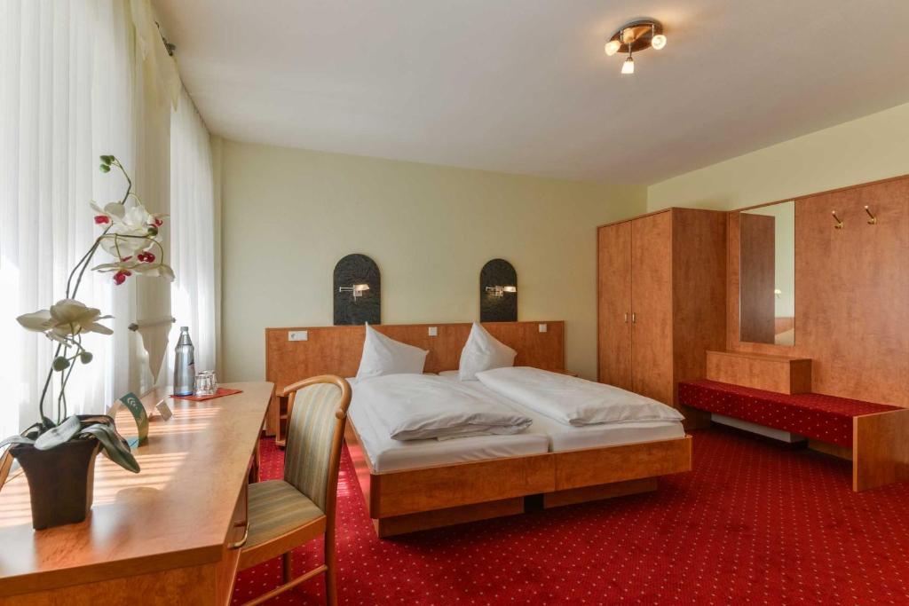a bedroom with a bed and a table and a desk at Hotel Kirchhainer Hof in Kirchhain