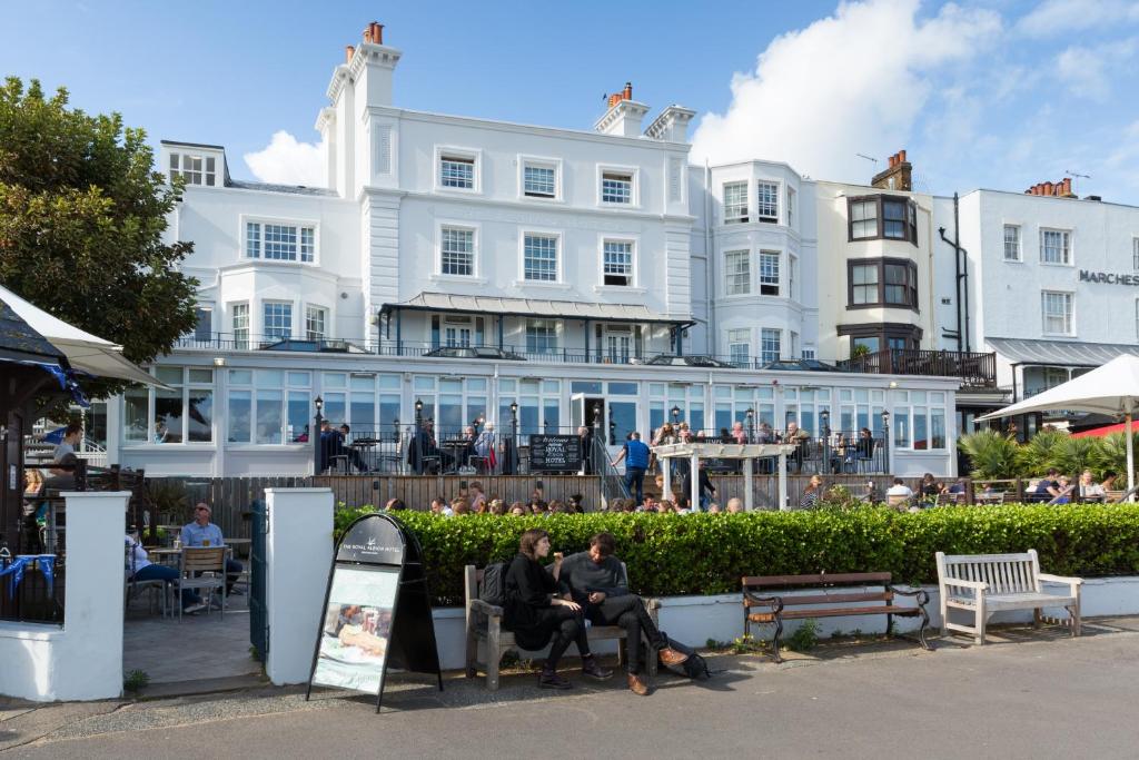 dos personas sentadas en bancos frente a un edificio en The Royal Albion, en Broadstairs