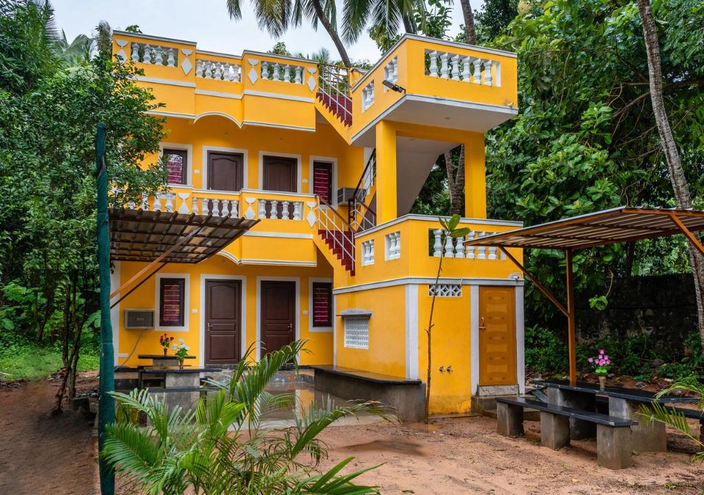 a yellow house with a balcony on top of it at Pavisha Farm House Swimming Pool in Pondicherry