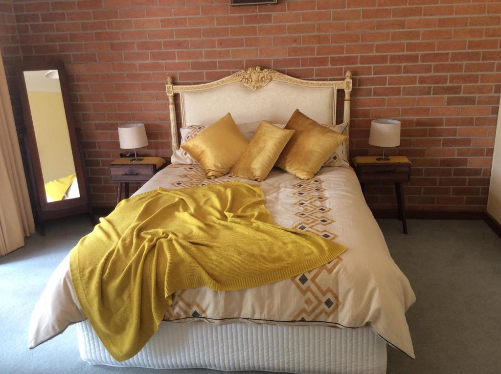una camera da letto con letto, lenzuola e cuscini gialli di Dunolly Broadway B&B a Dunolly