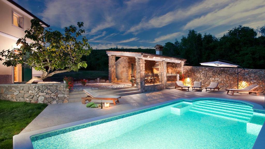 a swimming pool in a yard next to a house at Charming villa Bea with private pool and volleyball in Koromačno