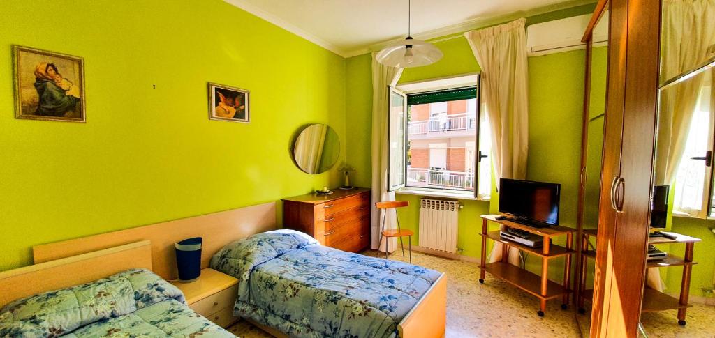 1 dormitorio con paredes verdes, 1 cama y TV en Casa degli Aranci, en Sorrento