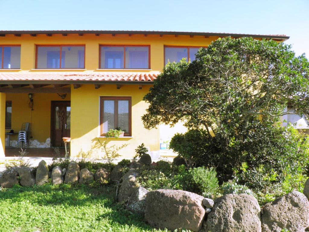 a yellow house with rocks in front of it at Casa Casti in Sant' Antonio di Santadi