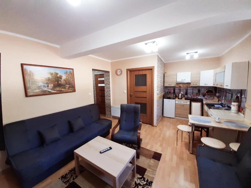 a living room with a blue couch and a kitchen at APARTAMENT ELIZABETH in Kościelisko