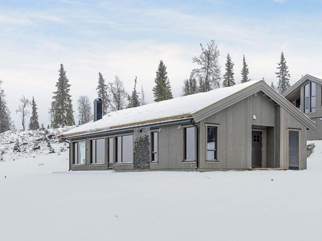 a house in the snow with trees in the background at 10 person holiday home in F vang in Favang