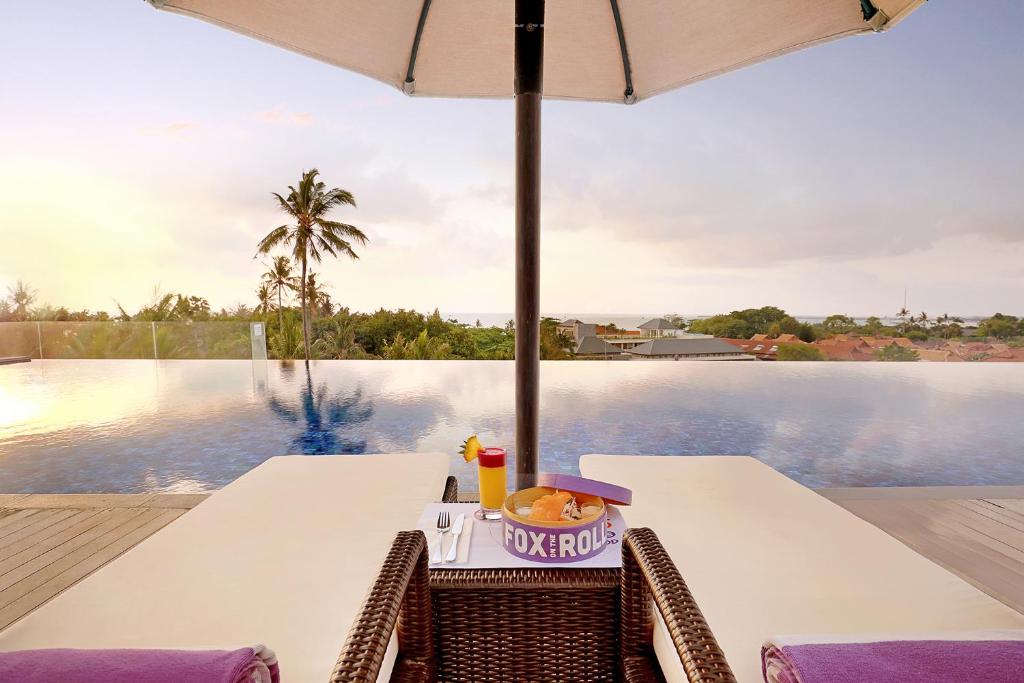 una mesa con un plato de comida y una sombrilla en FOX Hotel Jimbaran Beach en Jimbaran