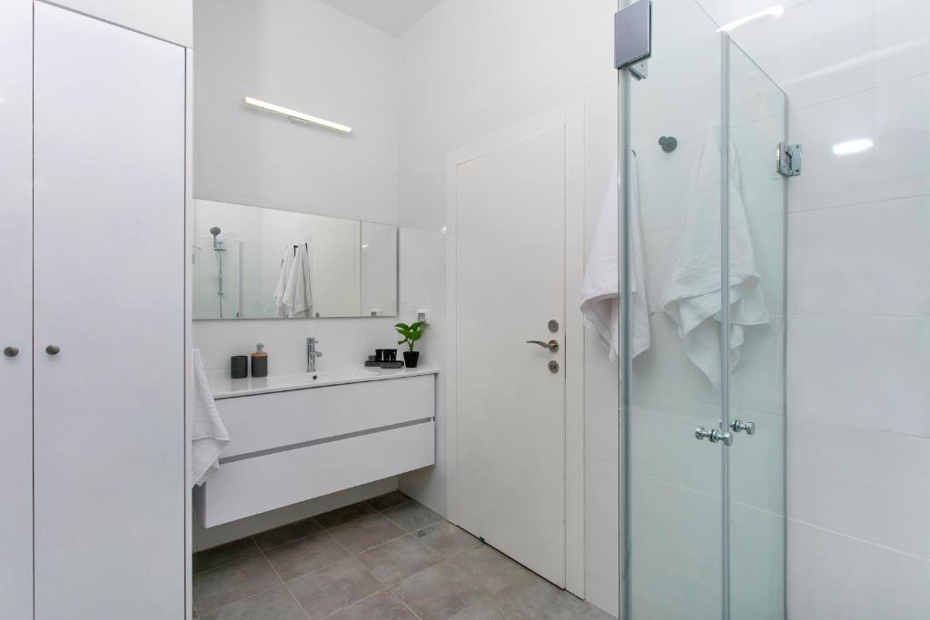 a white bathroom with a shower and a sink at Mr Allenby By TLV2GO in Tel Aviv