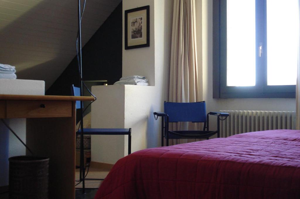 a bedroom with a bed and two blue chairs at Albergo della Posta in Astano