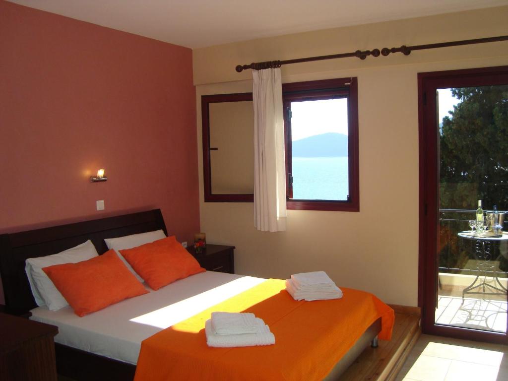 ein Schlafzimmer mit einem Bett mit orangefarbenen Kissen und einem Fenster in der Unterkunft Mikros Gialos Apartments in Mikros Gialos