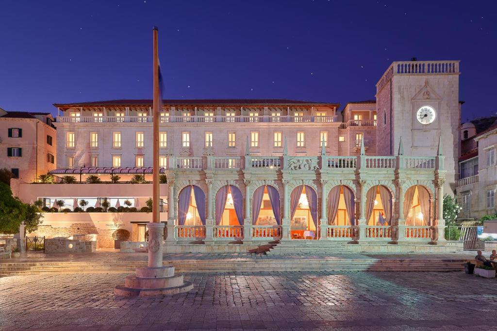 un grande edificio con torre dell'orologio di notte di Palace Elisabeth, Hvar Heritage Hotel a Hvar